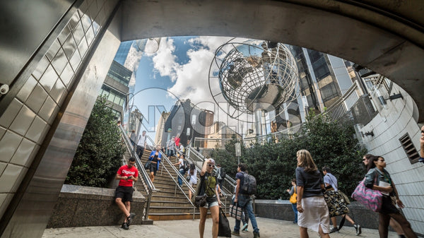 Columbus Circle with famous globe sculpture and people in Midtown Manhattan on sunny summer day from subway station stairs in NYC
