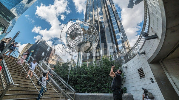 Columbus Circle with tourist photographer taking photo - famous globe sculpture and Trump Tower and people in Midtown Manhattan on sunny summer day from subway station stairs in NYC