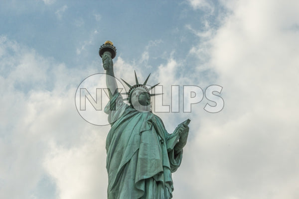 Statue of Liberty - medium shot at upward angle over blue sky with clouds on bright sunny day