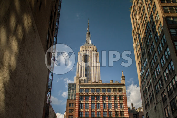 Empire State Building view from between two buildings in alley on bright sunny day