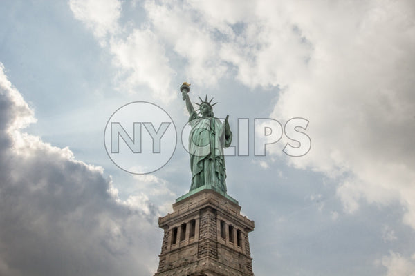 Statue of Liberty - long shot upward angle - beautiful bright day with blue sky and clouds - full view with base