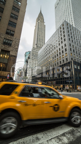 yellow caravan taxi cab driving past Chrysler Building skyscraper in Midtown Manhattan