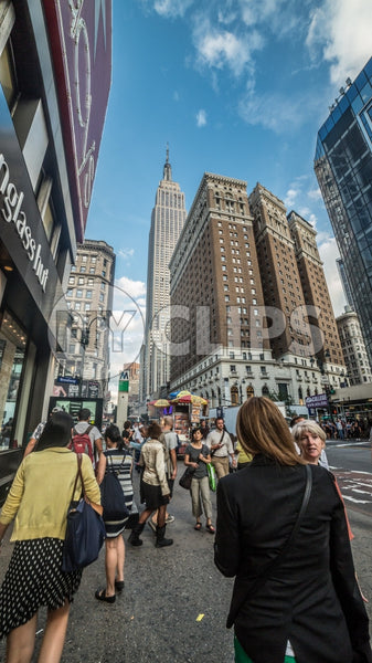 Empire State Building towering over 34th street and Herald Square on crowded busy street on summer day in Manhattan