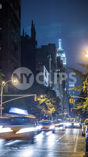 Empire State Building with blur motion taxi cabs driving down Lower Fifth Ave at night in Manhattan