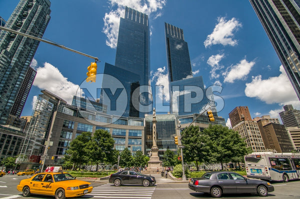 Time Warner Towers at Columbus Circle during day, blue sky in summer with cars and taxi cab driving around circular street