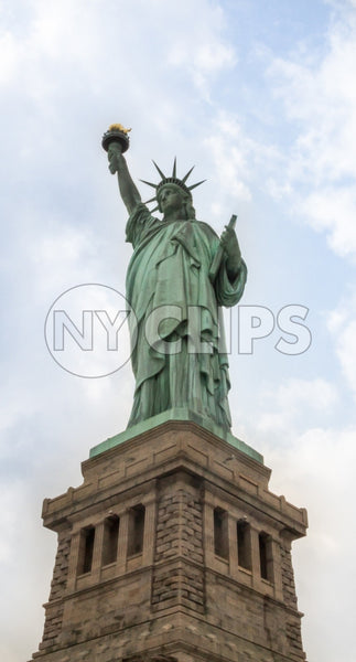 Statue of Liberty full view head to toe with base over blue sky and clouds during day