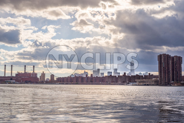 view of Freedom Tower in Manhattan skyline with red brick buildings from across river water - smoke stacks on bright sunny day with blue sky and clouds