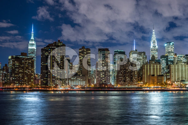 Empire State Building and Chrysler famous skyscrapers in Manhattan skyline from across East River water at night