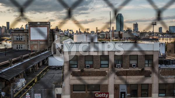 gritty view of Brooklyn through fence at sunset with Manhattan buildings and skyscrapers in background in NYC