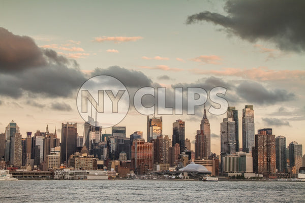 Manhattan skyline at sunset in early evening with Empire State Building and beautiful clouds overhead in NYC