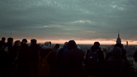 silhouettes of tourists looking at Manhattan cityscape from observation deck high up on chilly fall day at sunset in NYC
