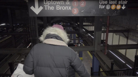woman in coat and hat walking down subway station stairs with Uptown and The Bronx sign for 1 2 and 3 train lines - 4K and 1080 HD in NYC