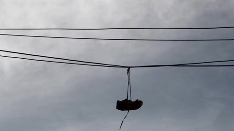 shoes hanging from wire - silhouette of sneakers on line