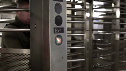 Latino man entering subway station revolving turnstile in slow motion