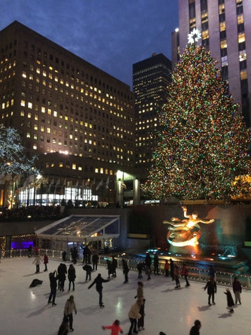 people in ice skating rink in Rockefeller Center with Christmas tree lit up - winter holidays at night