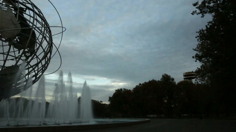 panning across globe sculpture in Flushing Meadows Corona Park with water sprinklers in Queens New York at beautiful sunset in early evening