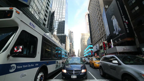 bus and cars driving through Times Square traffic on summer day