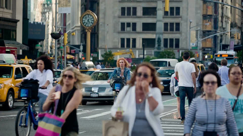 crowded busy summer street in Manhattan with famous clock on 23rd Street