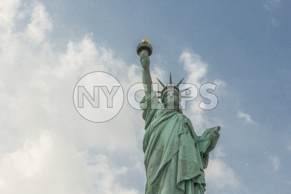 Statue of Liberty - medium shot from waist up over blue sky with clouds on bright day
