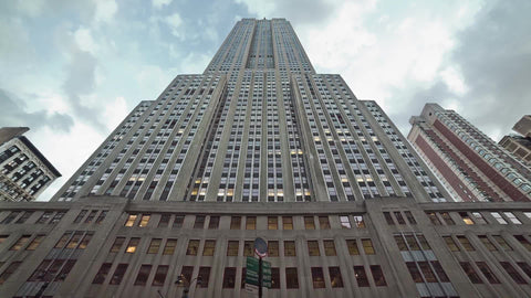 Empire State Building - upward view tilting down to street - people walking on 34th st in summer early evening