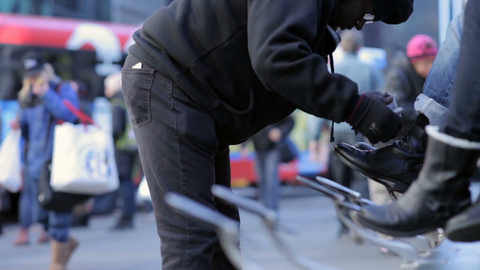 shoe shiner in Bryant Park in winter during day shining shoes and boots in NYC