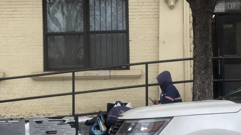USPS postal worker - mailman woman delivering mail on cart in street texting in New York City NYC