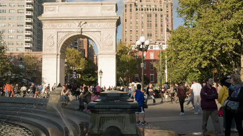 famous arch in Washington Square Park on bright sunny day - crowded with people playing frisbee in summer