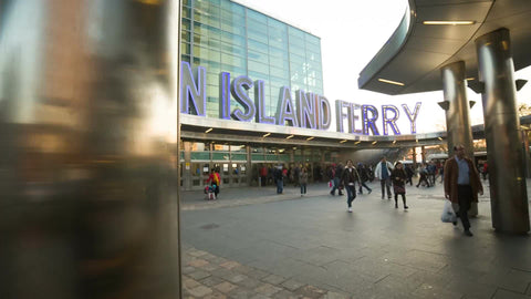 large sign for Staten Island Ferry and commuters walking at rush hour on cloudy spring or fall day in 1080 HD NYC