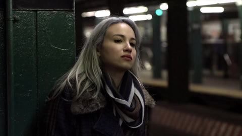 tired woman standing waiting for subway on train station platform in winter with coat and scarf