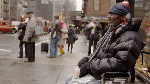 homeless man with oxygen tank in wheelchair begging for change with cup on cold winter day in Manhattan street in 4K NYC