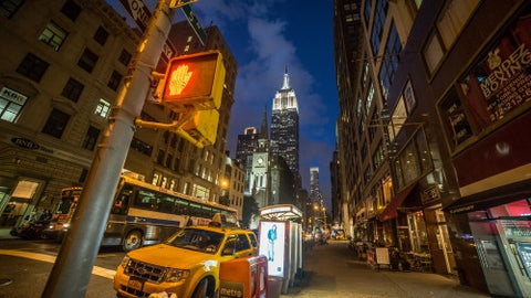 Empire State Building at night on 5th Avenue with taxicab parked on corner in Manhattan