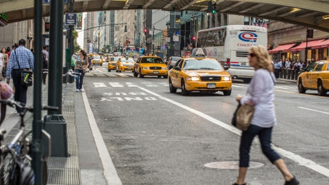 woman crossing street in Midtown outside Grand Central Station with taxi cabs driving in Manhattan