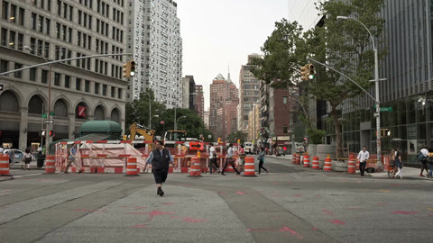 bus driver walking across Cooper Square with orange construction cones in Manhattan