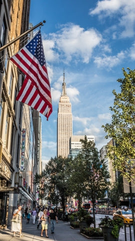 Empire State Building and American flag - summer day in Manhattan - street view of tall landmark skyscraper