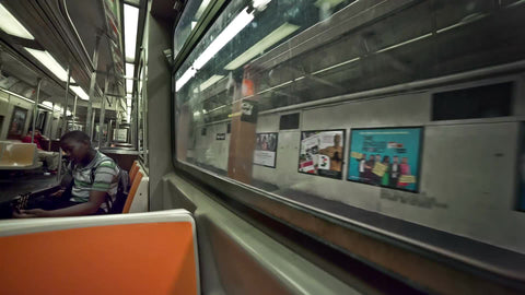 musician kid riding subway train tuning his guitar - interior in summer NYC