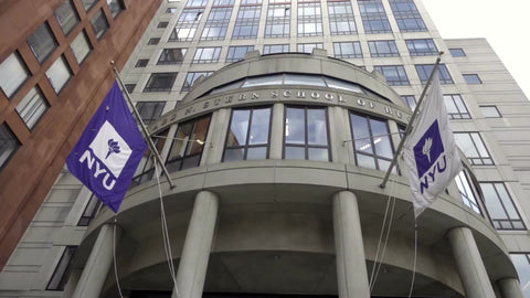 NYU flags tilting down to Stern School of Business building circular entrance