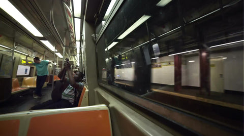 musician tuning his guitar on moving subway train interior in summer - NYC