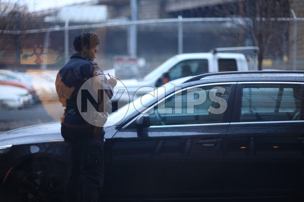 female police officer writing ticket on car windshield - NYPD cop giving summons