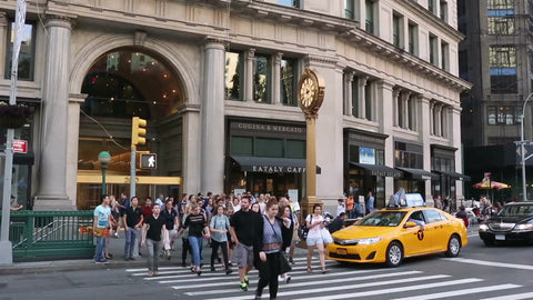 people crossing street at 5th Ave crosswalk with famous clock - man taking picture on summer day