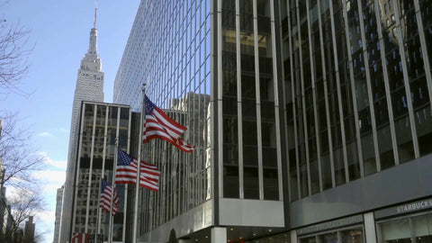 American flags waving on 34th street outside corporate office building with Empire State Building landmark in background, Manhattan NYC 1080 HD