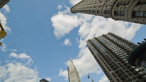 rotating shot of Flatiron Building and other skyscrapers on 5th Ave in Manhattan - street view upward blue sky on summer day