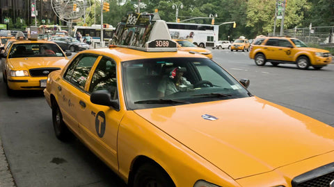taxi cabs in taxicab stand at Columbus Circle with cars driving by in Manhattan traffic in NYC