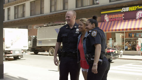 police officers posing with tourist woman while husband takes photo on summer day - 5th ave in Manhattan NYC
