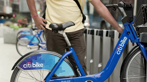 man renting Citi Bike on summer day - close-up on parked blue bicycle in NYC