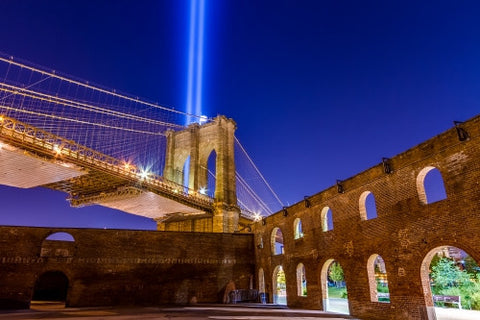 abandoned gritty park at night with Brooklyn Bridge and 911 lights - beams in night sky