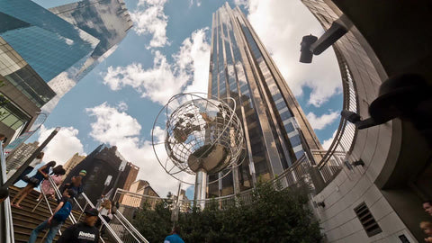 upward view of Trump Tower and steel globe sculpture at Columbus Circle subway station in Midtown Manhattan on summer day - beautiful sky and clouds in NYC