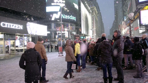 snow flakes falling on Times Square with big LCD screen - tourists looking up at Revlon ad at night