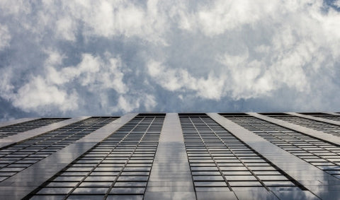 tall skyscraper with clouds in sky - upward view