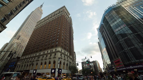 no left turn sign and busy traffic in Herald Square on summer day with Empire State Building towering overhead in NYC