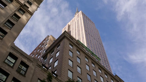 Empire State Building towering over 5th Ave buildings - famous skyscraper on bright sunny day in Manhattan